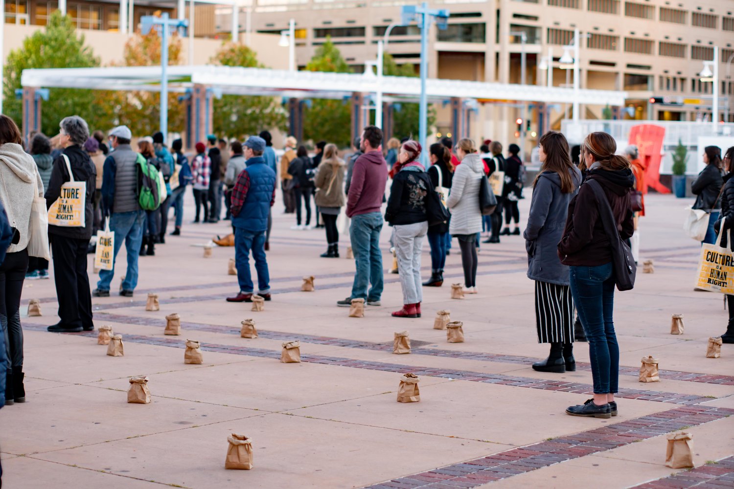 Standing with 'Culture is a Human Right' tote bags among a spiral of luminarias during the opening ceremony